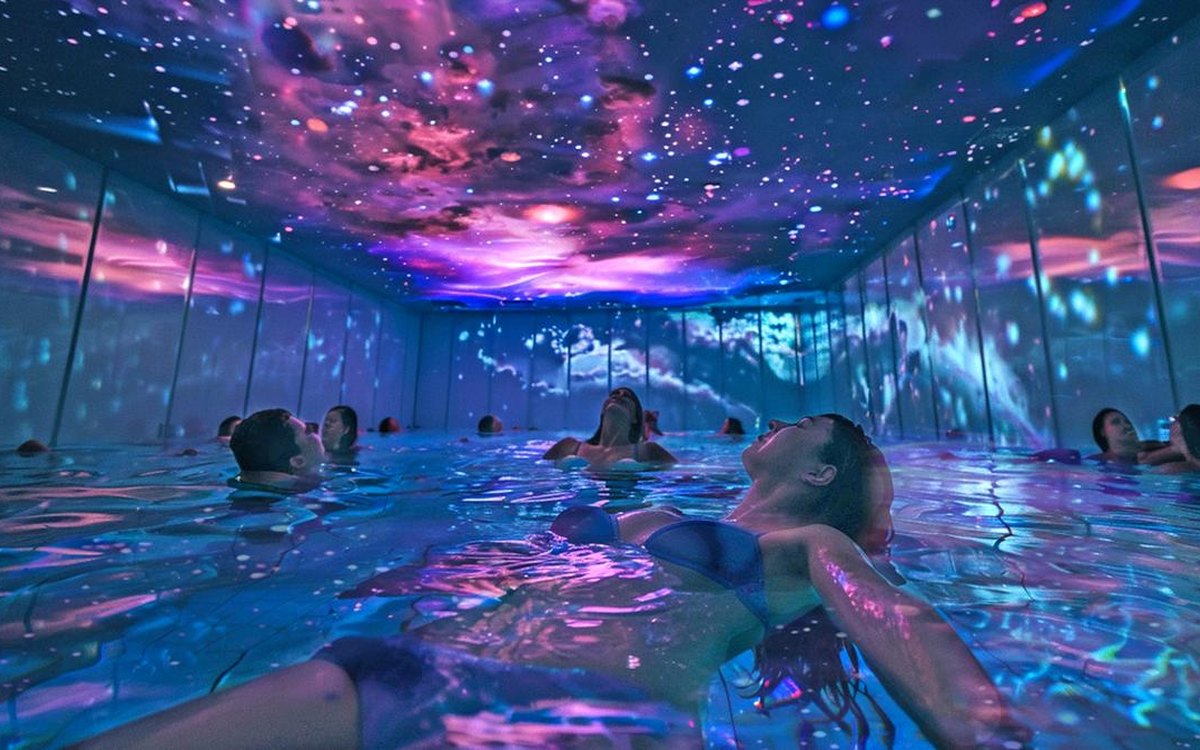 People floating in a projected, immersive bathhouse
