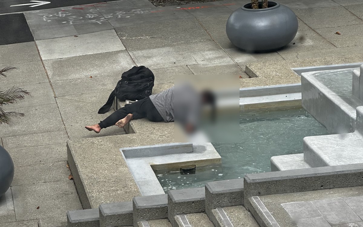 A person washing at a public fountain
